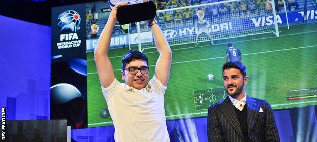 Mohamad Al-Bacha of Denmark lifts his champion trophy presented by David Villa during the Grand Final of FIFA Interactive World Cup