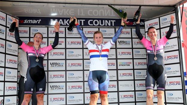 Hayley Simmonds celebrates on the podium, with Claire Rose and Dame Sara Storey on either side