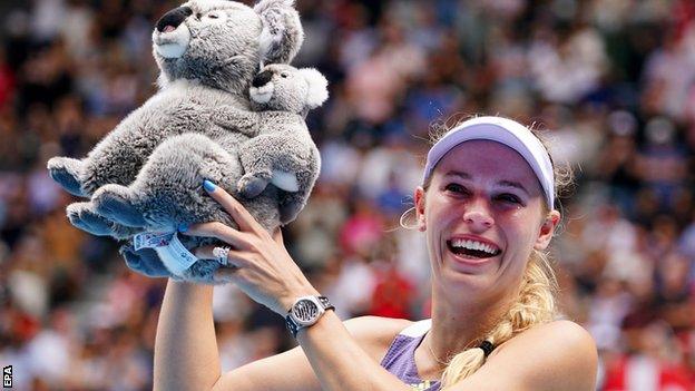 Caroline Wozniacki poses on court with a toy koala bear after losing to Ons Jabeur at the Australian Open