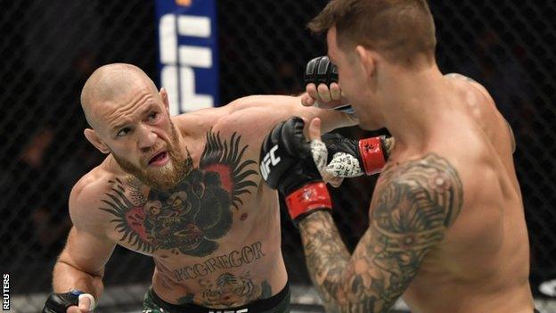 Conor McGregor punches Dustin Poirier during their fight at UFC 257