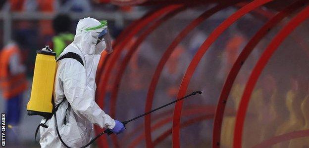 A worker wearing personal protective equipment sanitise the dugouts in Yaounder