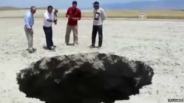 Local men looking into a sinkhole