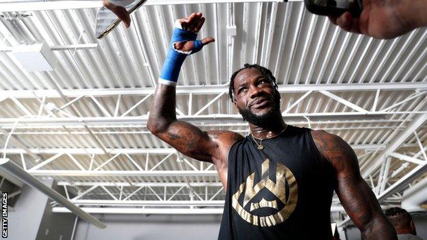 Deontay Wilder throws his hand in the air speaking