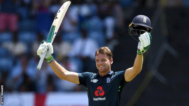 England batsman Jos Buttler raises his bat and helmet in celebration after hitting a century in the fourth ODI against West Indies