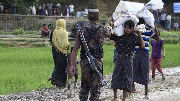 A Bangladesh border guard attempts to clear Rohingya Muslim refugees off a road near a refugee camp