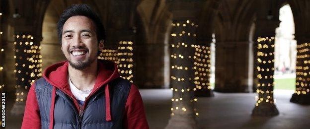 Aaron Fernandez, a Glasgow 2018 volunteer, standing with cloisters in the background.