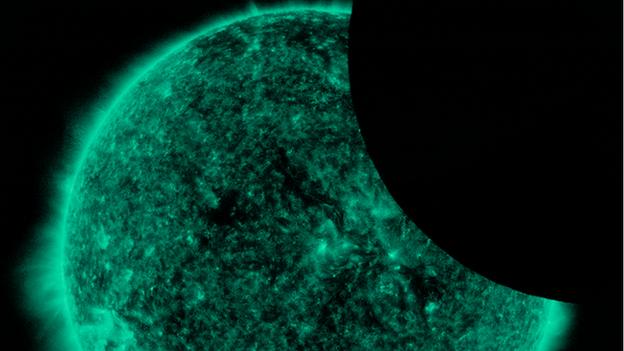 A green Sun with a round shadow across the top right-hand corner