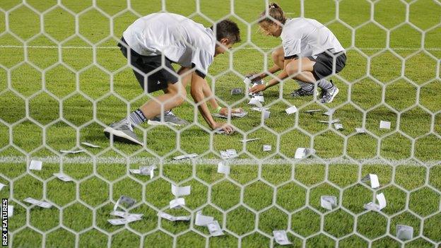 A ball boy and girl remove the fake notes during a brief break in play