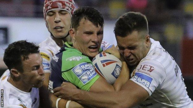 Louis Senior for Huddersfield, flanked by Catalans tacklers