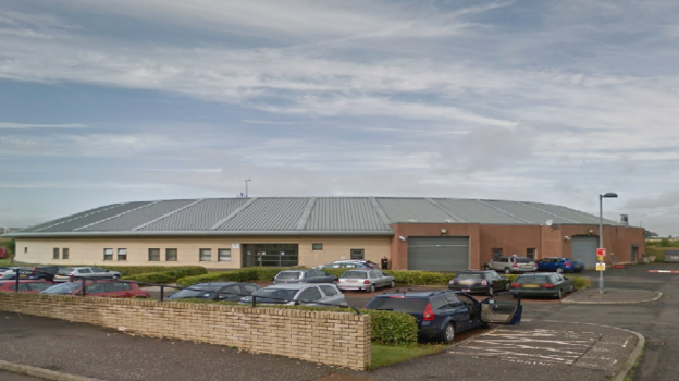 St Mary's Kenmure  secure unit in Bishopbriggs, East Dunbartonshire - the view shows the car park with several cars parked, and the building itself, with sandstone walls and a grey roof.