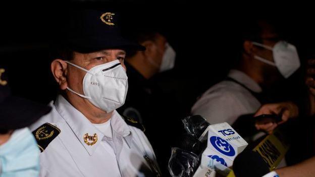 National civil police director Mauricio Arriaza Chicas (C) speaks with the press at the crime scene where unknown men murdered six people inside a bar in La Isla neighborhood in San Salvador on 11 October 2020