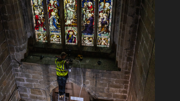 Worker in hi-vis jacked working on stained glass window at St John the Baptist Church