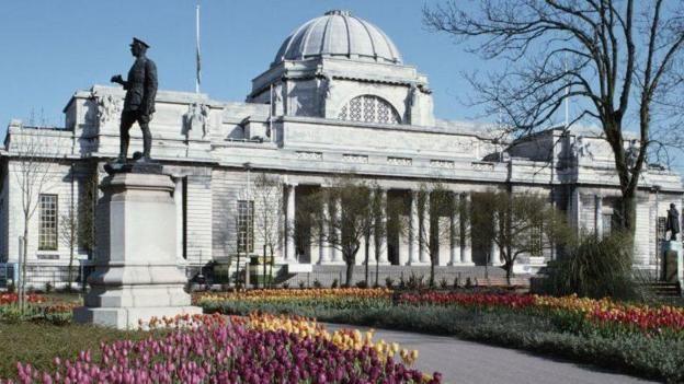 A general view of the front of the National Museum in Cathays Park, Cardiff, with a statue in front.