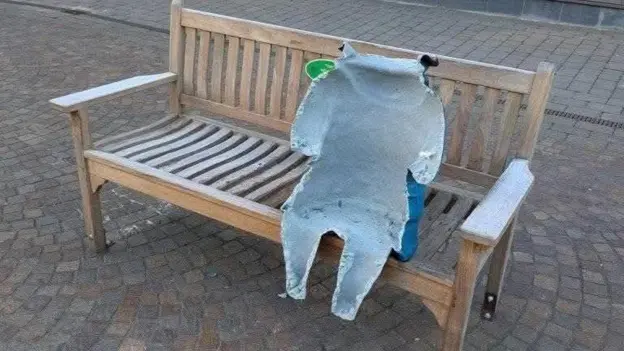 The damaged statue of Paddington on its bench. Only part of it is left, with the front completely torn off.