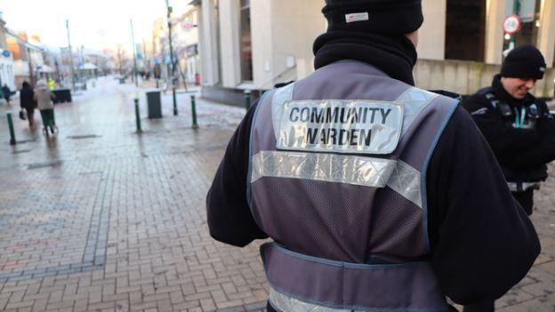 The back of a litter enforcement officer with a purple high-vis vest saying 'community warden' in Scunthorpe town centre  