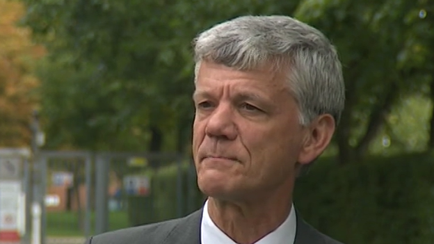 Tim Coulson looks away from the camera while standing outside. He has short grey hair and wears a grey suit jacket with a white shirt and tie.