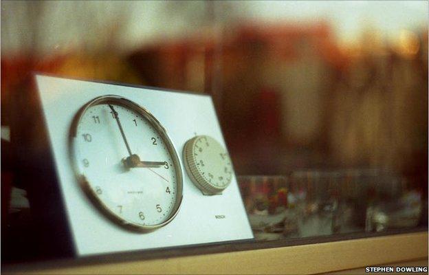 A clock in winter sunlight in the window of a second hand store in Berlin