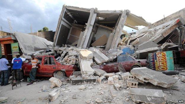 A group of men standing in rubble after an earthquake in Haiti.