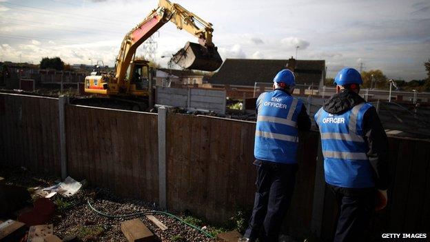 digger and two men stood by fence