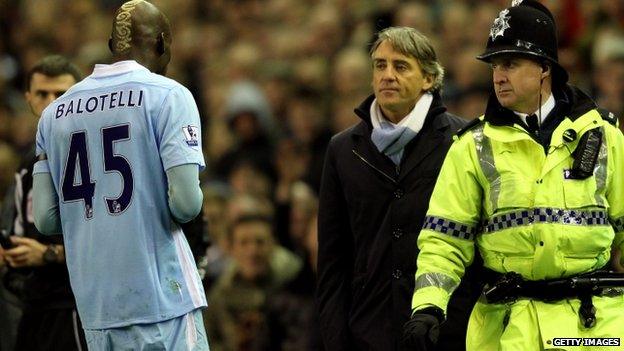 Roberto Mancini looks at Mario Balotelli as he heads for the dressing room
