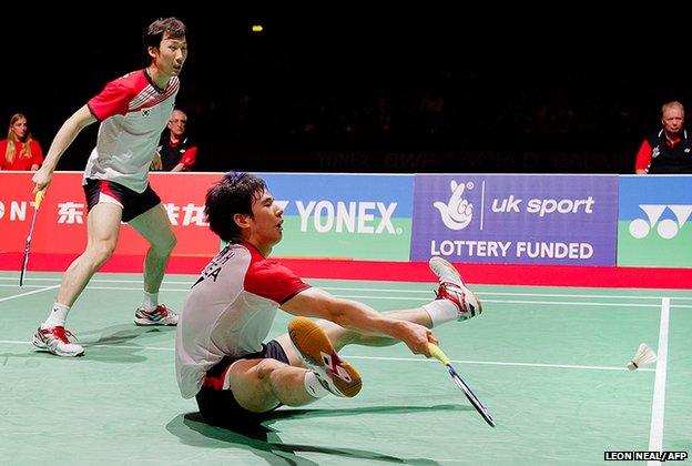 Ko Sung Hyun (seated) of Korea returns a shot to Mohammad Ahsan and Bona Septano of Indonesia (not pictured) during the men's doubles semi-finals from a rather unconventional position at the World Badminton Championships at Wembley Arena