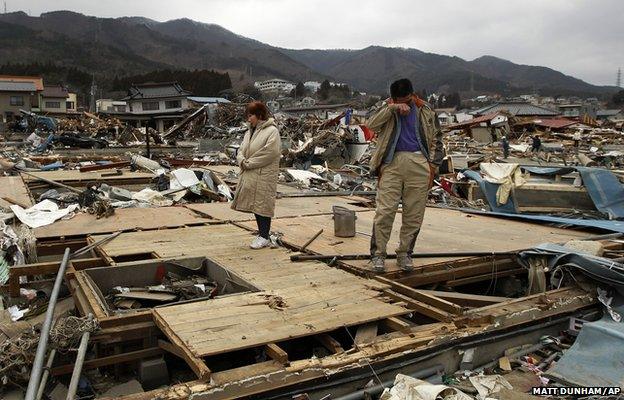 Keijo Nakamura (right) and his wife Haruka react as they stand on the remains of a relative's home in Ofunato