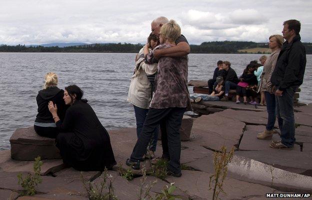 People gather to observe a minutes silence across the water from Utoya island where Anders Behring Breivik killed at least 68 people, many of whom were teenagers attending a summer youth camp on the island