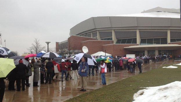 a line forms in front of a building on a rainy day