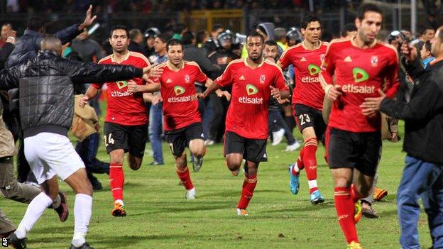 Players run for safety as violence erupts in the match between Al-Masry and al-Ahly