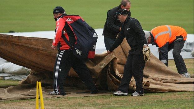 Ground staff cover the pitch at Queens Park