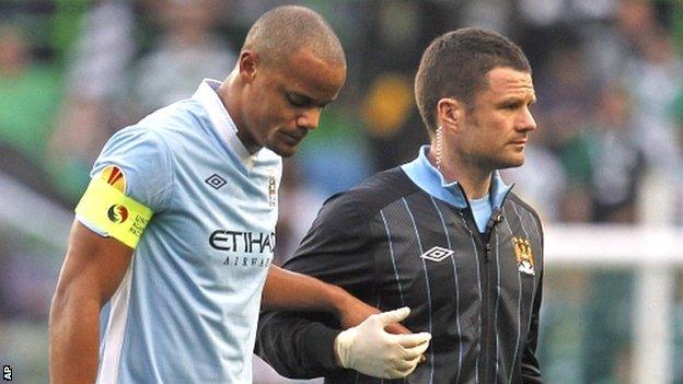 Kompany (left) is helped from the pitch after injuring himself in Portugal