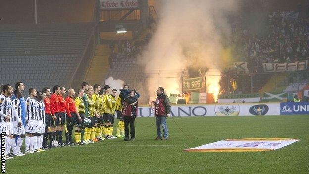 Celtic fans let off a firework and display an offensive banner