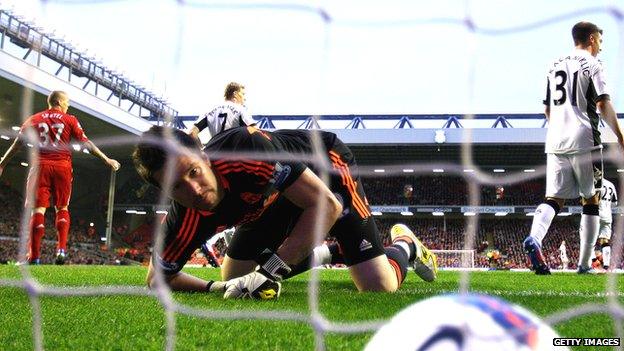 ball in net as goalie looks down at it. Skrtel stands with arms outstretched in background