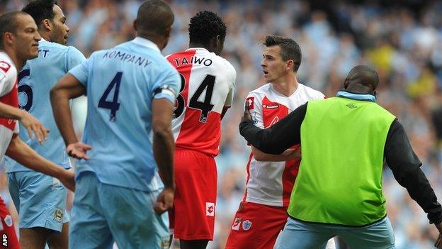 QPR midfielder Joey Barton is led away by Manchester City substitute Micah Richards