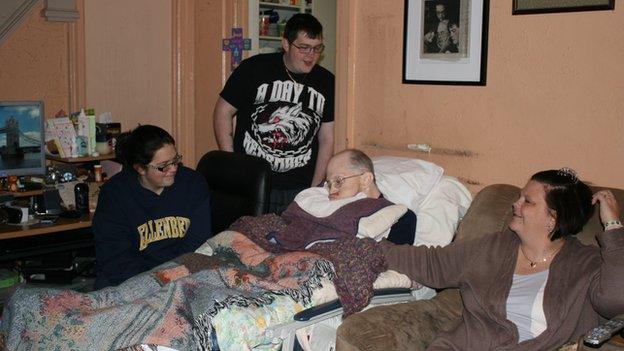 A man with Alzheimer's sleeps on the couch while his family watches