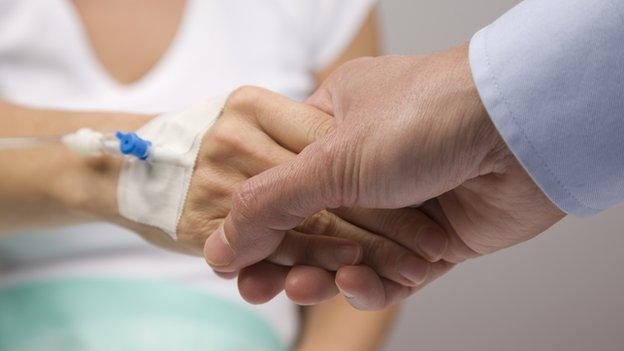 Man holding a patient's hand (with drip)