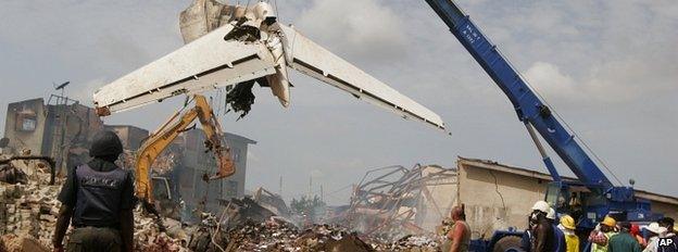 People watch as a crane lifts the tail of a plane after it crashed at Iju-Ishaga neighbourhood in Lagos 4 June 2012