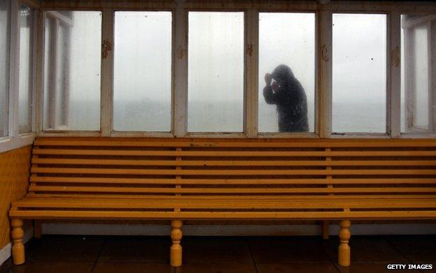 Man in cagoule on rainswept pier