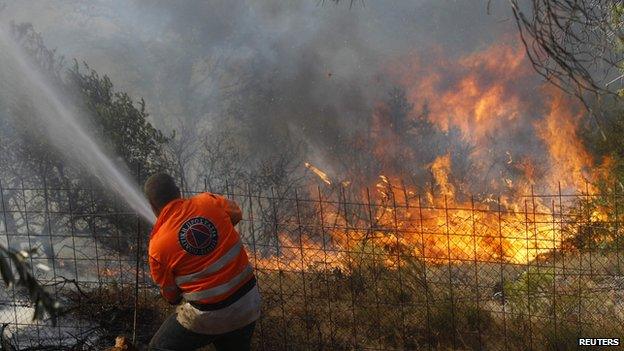 A man spray water on a wildfire in Greece