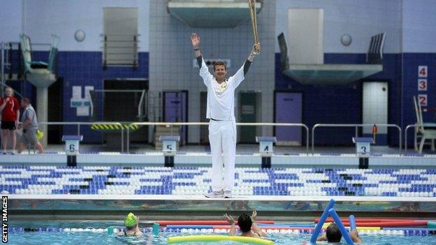 Former Olympian Steve Cram holds the Olympic Torch aloft at the Sunderland Aquatic Centre