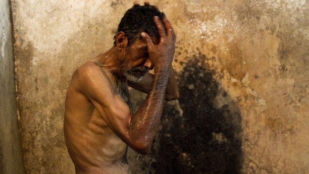 A heroin addict showers takes a shower at the Edhi rehabilitation centre in Karachi