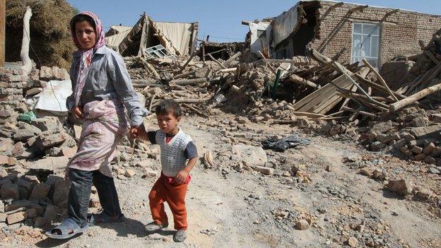 Woman and child walk near rubble of house destroyed by the earthquake
