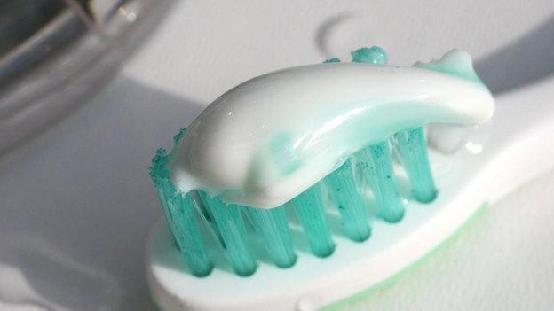 A strip of toothpaste sitting on top of tooth brush bristles.