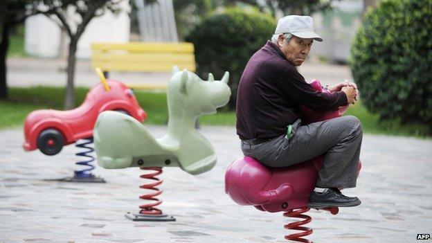 An elderly man rides on a toy horse in Beijing on 9 September 2012