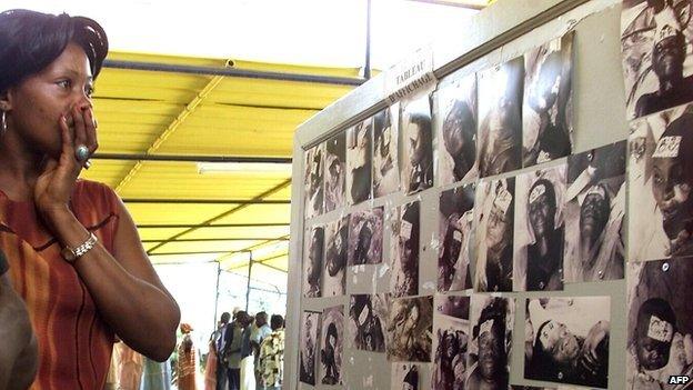 A woman looks at photos of people who died in the Joola ferry disaster - photo taken on 29 September 2002