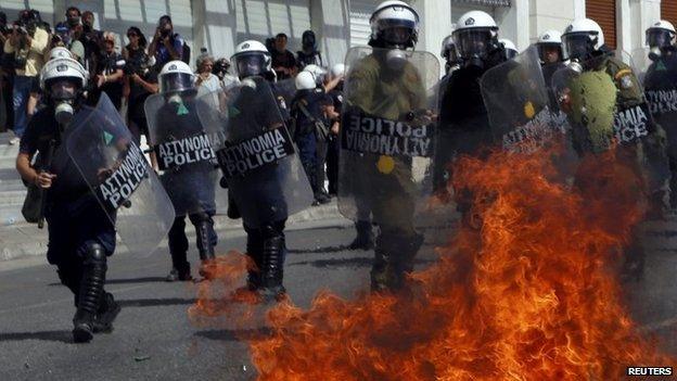 A petrol bomb explodes beside riot police officers near Syntagma square during a 24-hour labour strike in Athens, 26 September 2012