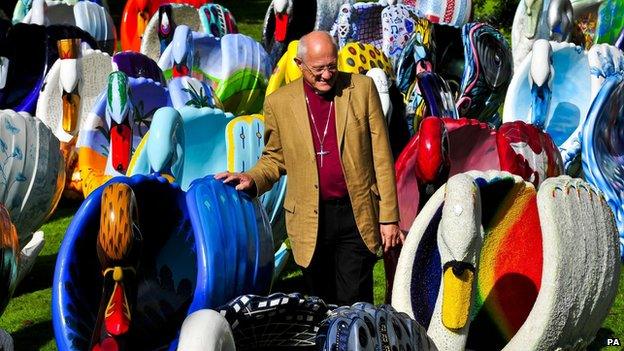 The Bishop of Bath and Wells, Peter Price, checks out the giant flock of around 60 brightly coloured swan sculptures in the grounds of the Bishops Palace, Wells.