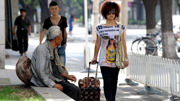 Rich woman walks down a Chinese street next to a poor man