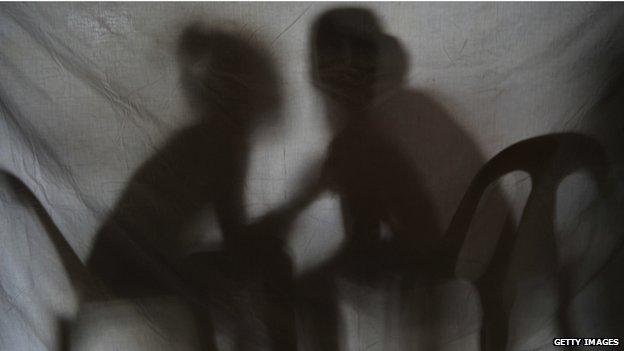 Silhouette of two girls rescued from a sex trafficking ring talking behind a screen