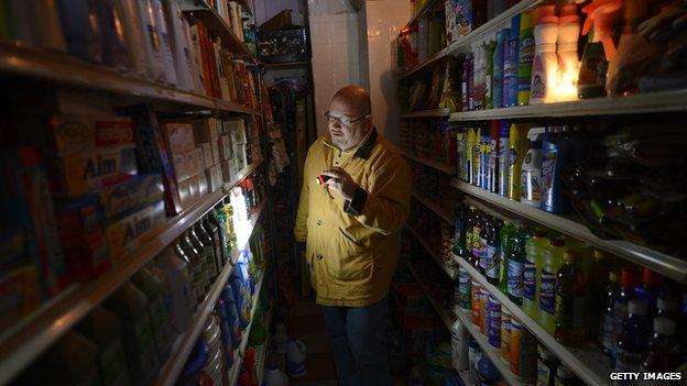 A man shops for groceries using a flashlight